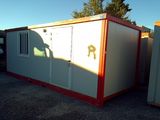 two portable buildings in a parking lot with a person standing in the doorway