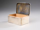 an old silver box with a metal lid sitting on a white surface
