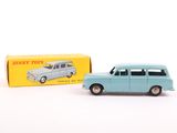 Une vieille petite voiture est posée à côté d'une boîte de Dinky Toys