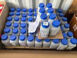 plusieurs bouteilles de lait posées sur une palette à côté d'un carton