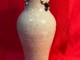 un vase marron orné de fleurs, posé sur un tissu rouge