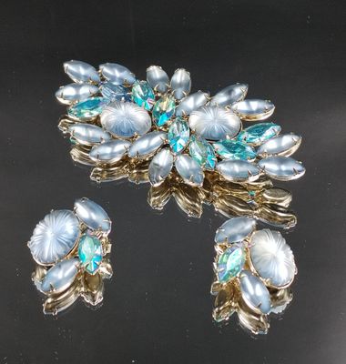 deux broches et une paire de boucles d'oreilles posées sur un fond noir