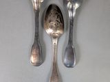 three spoons and two spoons sitting on a table