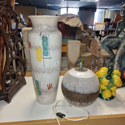 un vase blanc posé sur une table sur laquelle se trouvent d'autres objets