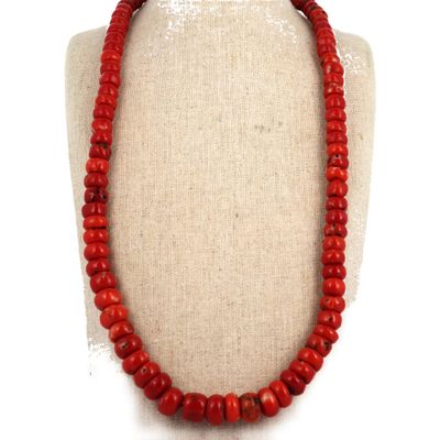 un gros plan d'un collier orné de perles rouges sur un mannequin