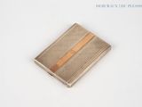 a silver and gold card case on a white surface