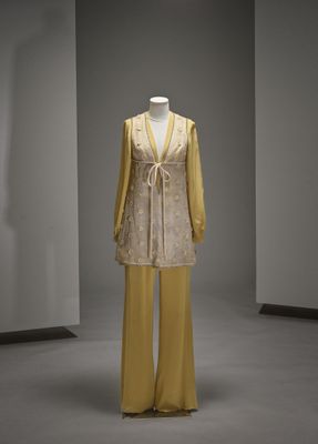 un mannequin vêtu d'une robe jaune et d'un pantalon jaune dans une pièce blanche