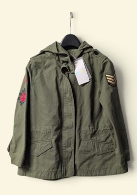 an army green jacket with patches and a tag on it