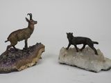 deux figurines d'animaux debout sur un rocher, avec un rocher au premier plan