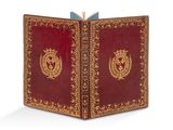 un vieux livre à la couverture rouge ornée d'un emblème doré