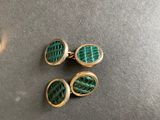 three pairs of green and gold cufflinks on a table