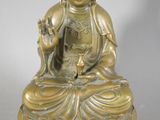 a gold statue of a buddha sitting on a rock