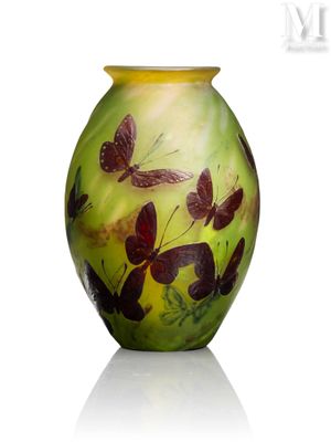 un vase vert orné de papillons, posé sur un fond blanc