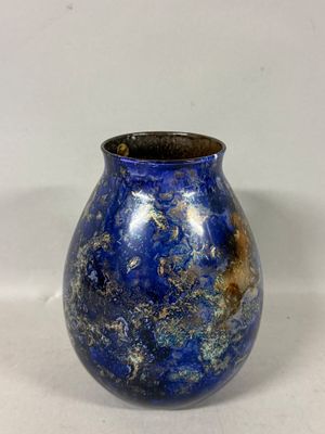 un vase bleu posé sur une surface blanche