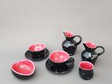 plusieurs tasses et soucoupes noires et roses posées sur une table