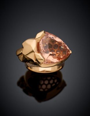 a close up of a gold ring with a pink diamond