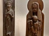 two wooden sculptures of a man and a woman holding a child