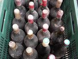 many bottles of wine in a green basket on the floor