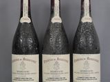trois bouteilles de vin sont alignées sur une étagère en verre