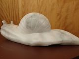 a white sculpture of a snail on a table