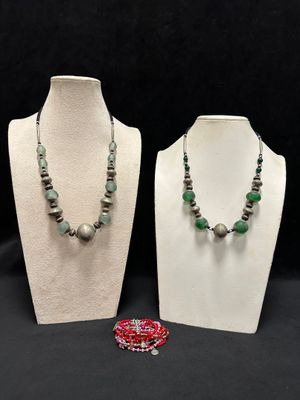 two necklaces and a bracelet on a mannequin stand