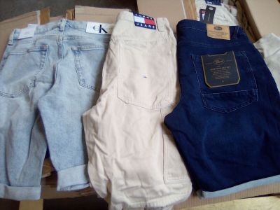 Trois paires de jeans pour homme sont posées sur un carton.