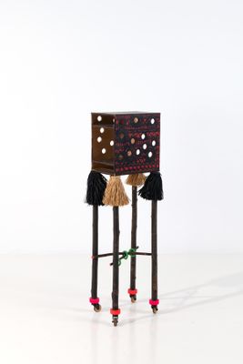 une image représentant un petit tabouret en bois dont les pieds sont ornés de pompons