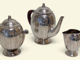 three silver teapots and a pitcher on a table