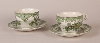 two green and white cups and saucers on a white surface