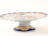a blue and white cake plate with a gold design on it