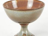 a brown and green bowl sitting on a white surface