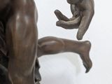 bronze statue of a man holding a fish on a rock