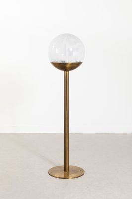 une lampe de table en laiton surmontée d'un abat-jour sphérique en verre