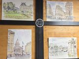 quatre tableaux accrochés au mur d'un immeuble sur lequel se trouve une horloge