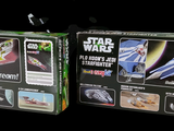 two boxes of star wars toys on a black background