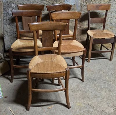 Plusieurs chaises en bois sont alignées contre un mur dans une pièce.