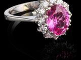 une bague ornée d'un saphir rose ovale et de diamants, posée sur un fond noir