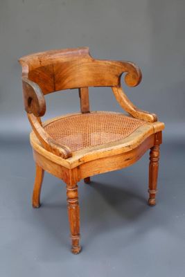 une vieille chaise en bois avec une assise tressée posée sur une surface grise