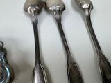 three silver spoons and two silver spoons on a white surface