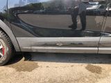 a man standing in front of a car with his reflection on the side of the car