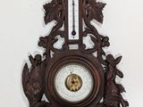 a wooden clock hanging on the wall next to a wall mounted thermometer