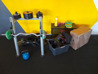 une salle de sport équipée d'une barre à disques, de kettlebells et d'autres appareils