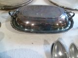 un plat en argent avec un couvercle et des cuillères sur une table