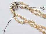 two strands of pearl beads with a silver clasp and a flower broocher