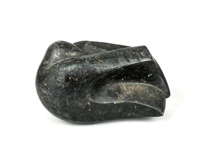 une sculpture en pierre noire représentant une main sur une surface blanche