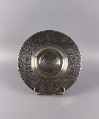 a silver plate on a stand on a white surface