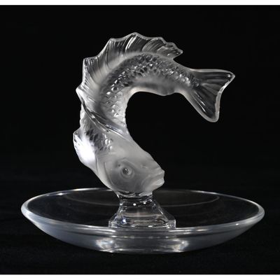 a glass sculpture of a fish on a clear plate