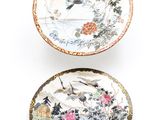 two plates with birds and flowers painted on them on a white surface