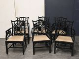 four black chairs with beige cushions sit in front of a white wall
