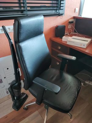 une chaise de bureau noire placée devant un bureau sur lequel se trouve un ordinateur